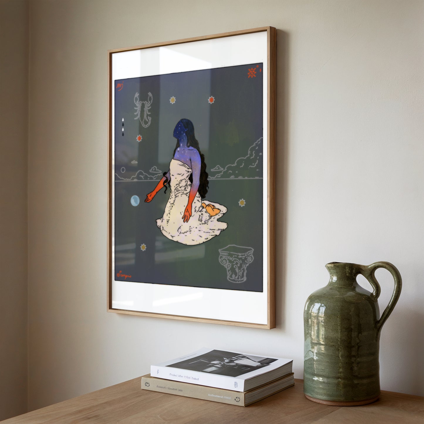 A framed art print featuring a stylized illustration of a woman in a white dress with orange-red arms, hanging on a beige wall above a wooden table with books and a green ceramic jug.