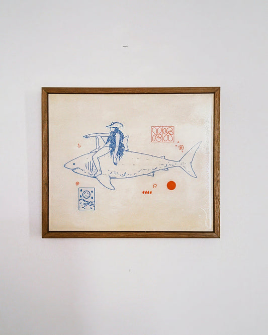 Framed artwork of a person riding a shark on a beige background